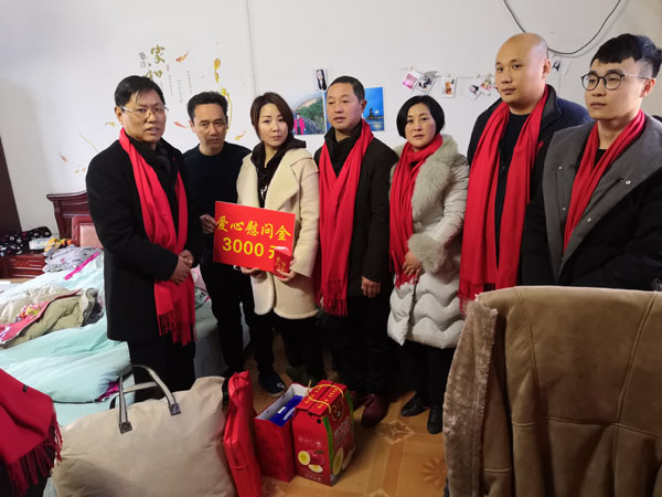 熊桂祥會長(左一)、徐敏秘書長（右三）、許生永經理（右二）、謝炳浩總助（右一）給楊白林特困戶家送上慰問金和慰問物品，圖為他們與長年臥病在床的楊白林夫婦的一雙整日侍奉兒女（左二、左三）及霍邱縣河口鎮領導（中）合影留念